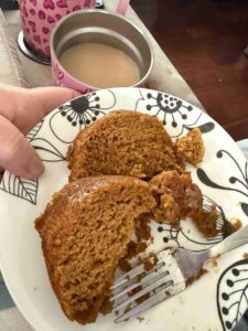 Two slices of pumpkin spice cake on a plate with a cup of coffee